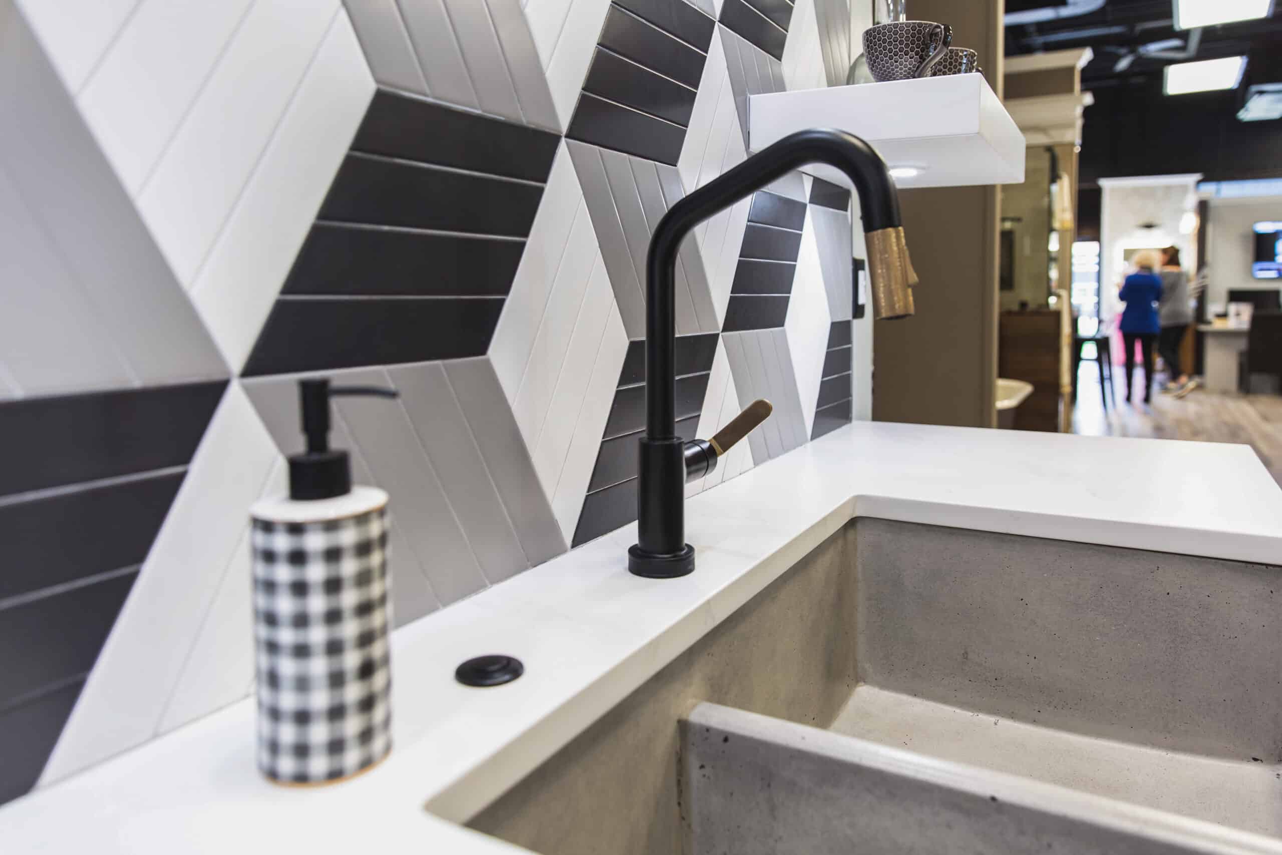 A kitchen sink with a black and white tile wall