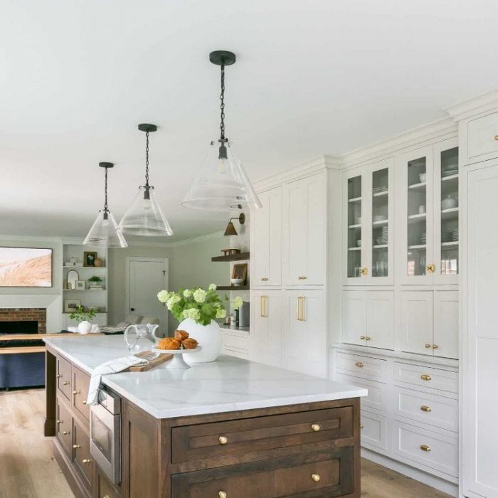 Transitional open-concept kitchen featuring a dark walnut island with a microwave drawer, white floor-to-ceiling pantry wall, and glass pendant lights.