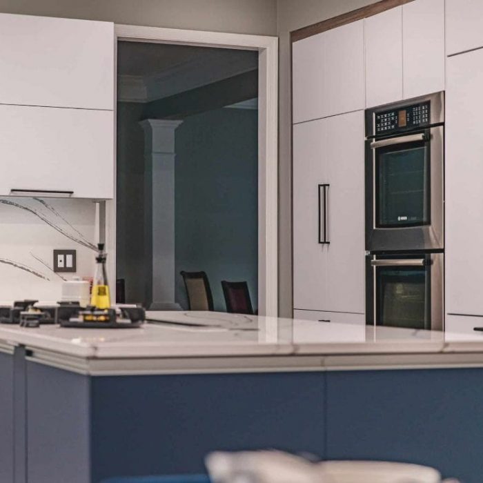 Modern Fairfax kitchen remodel featuring a navy blue island with gas cooktop, double wall ovens, and open-concept living room connection.