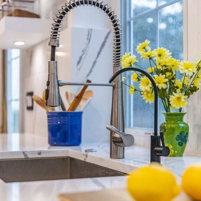 Fairfax kitchen renovation featuring a commercial coil faucet, matte black water dispenser, and quartz countertops by USA Cabinet Store.