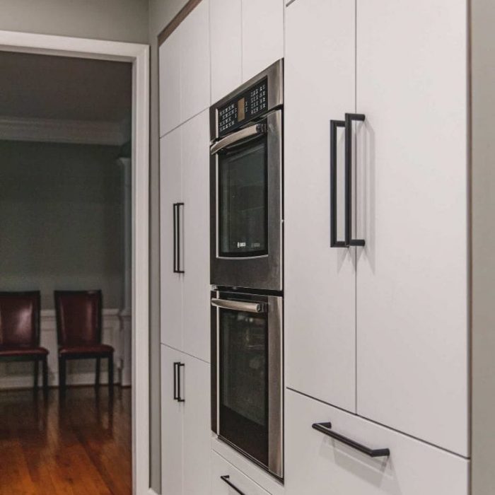 Fairfax kitchen remodel featuring a built-in Bosch double wall oven, white pantry cabinets with black bar pulls, and dark wood trim.