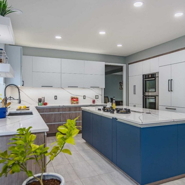 Modern Fairfax kitchen remodel featuring a navy blue island, tri-tone white and wood cabinetry, and full-height quartz backsplash.
