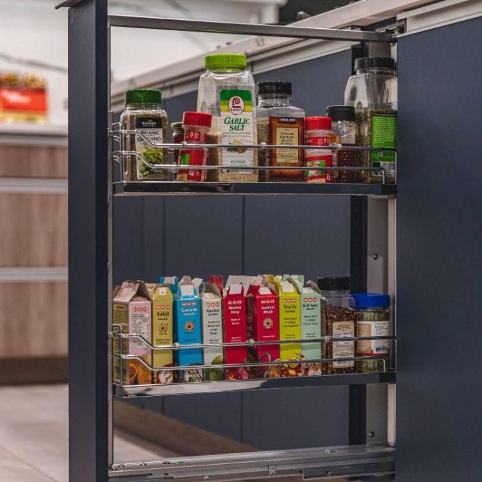 Fairfax kitchen island featuring a narrow pull-out spice rack cabinet with navy blue finish and aluminum channel handle.