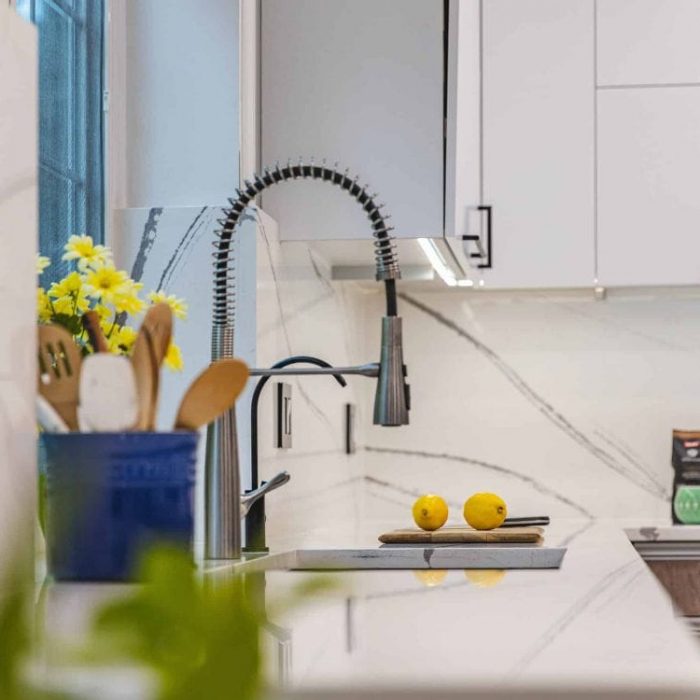 Modern kitchen remodel in Fairfax featuring a full-height quartz backsplash, commercial spring faucet, and under-cabinet lighting by USA Cabinet Store.