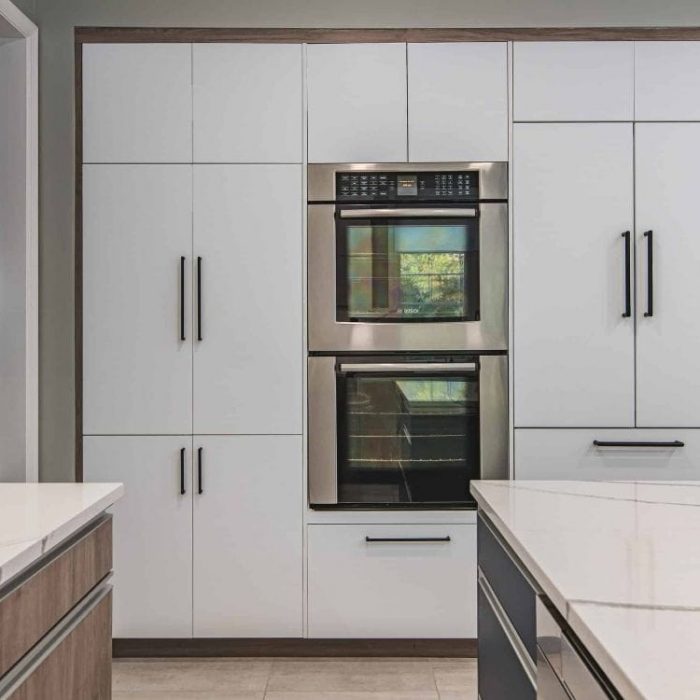 Fairfax kitchen renovation featuring built-in stainless steel double wall ovens surrounded by floor-to-ceiling white flat-panel pantry cabinets.