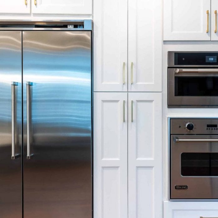 Built-in kitchen wall featuring a Viking refrigerator, JennAir microwave, and Viking wall oven surrounded by white Shaker cabinets.
