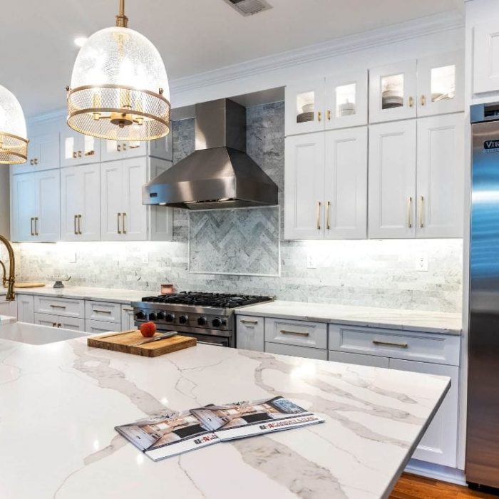 Luxury transitional kitchen with white shaker cabinets, charcoal island, Wolf range, and gold pendant lighting.