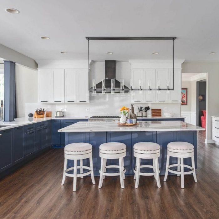 Luxury Leesburg kitchen by USA Cabinet Store with navy blue and white Shaker cabinets, quartz island, and black industrial hood.