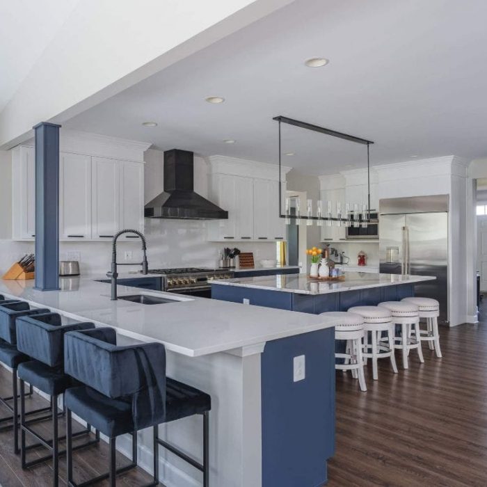 Luxury open-concept kitchen in Leesburg with navy blue double islands, white Shaker cabinets, quartz counters, and a built-in home bar.