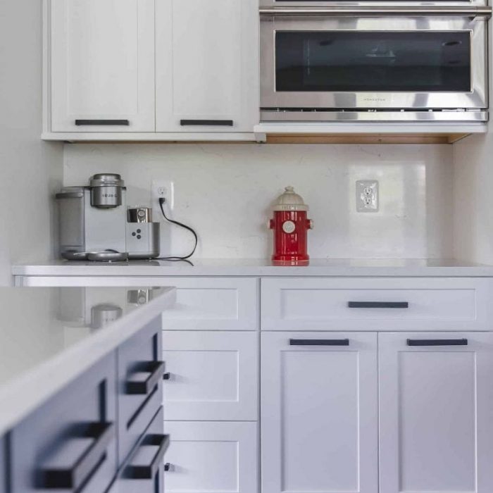 Navy blue kitchen peninsula with velvet bar stools, a prep sink, and a built-in beverage station with a draft tap.