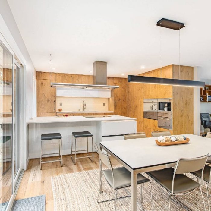 Modern open-concept home featuring a white and wood-grain kitchen, minimalist dining area, and adjacent home office.