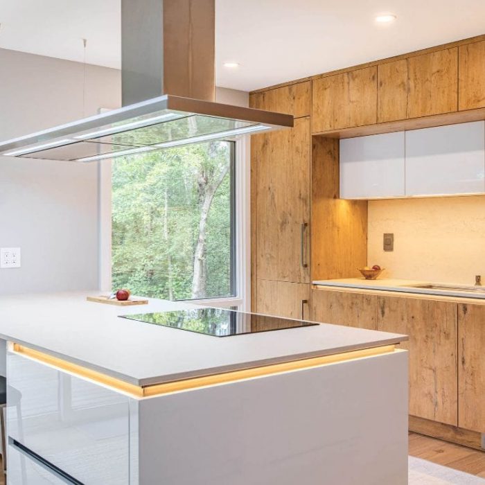 Modern kitchen workstation featuring natural wood-grain and white glossy cabinetry, integrated LED lighting, and a professional stainless steel sink.