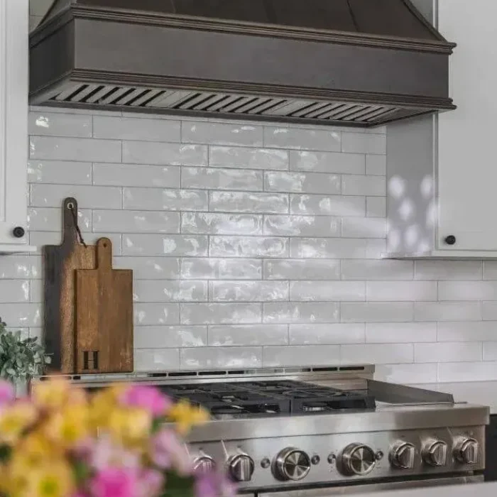 Park Creek Miyuki kitchen detail with professional gas range, white subway tile backsplash, and dark range hood